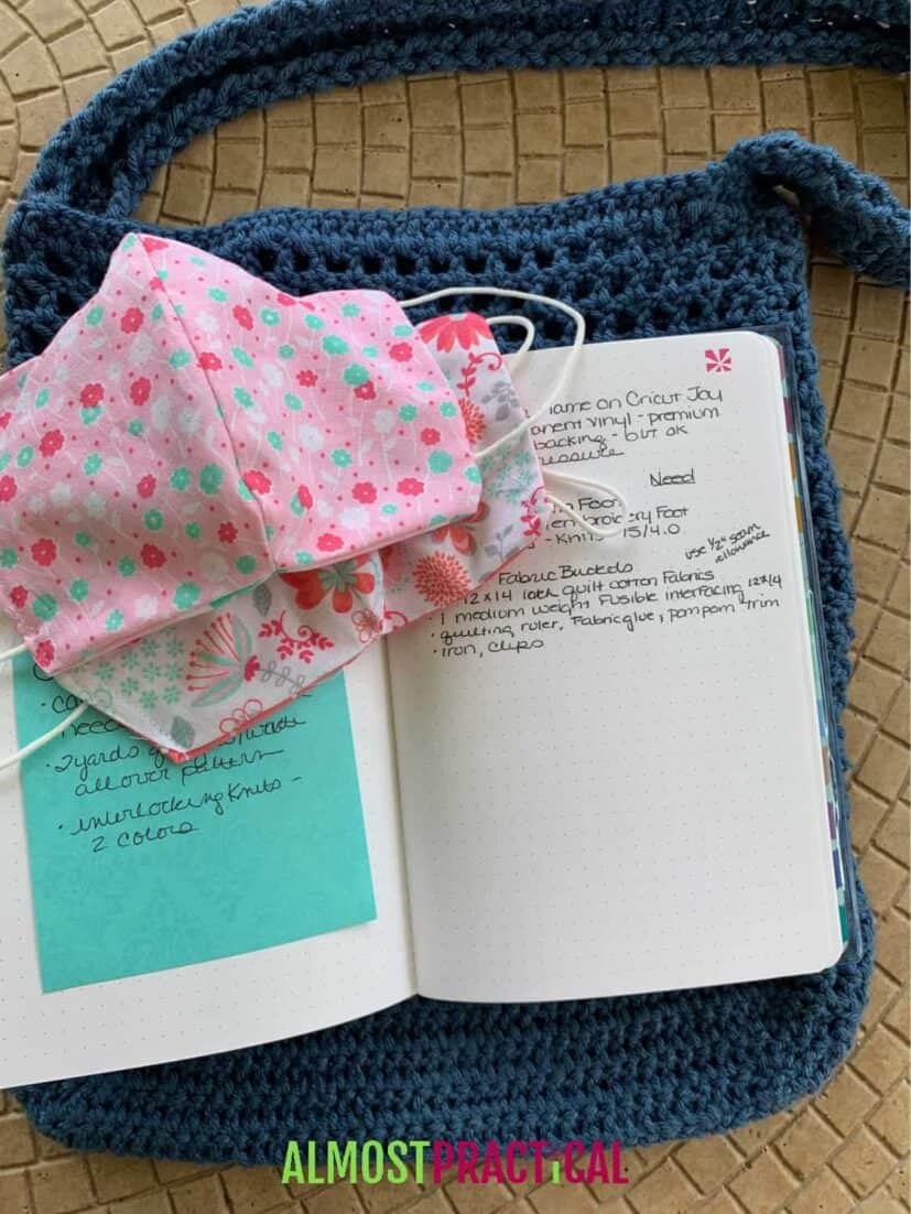 dot grid notebook with crochet purse underneath and cloth face masks on top