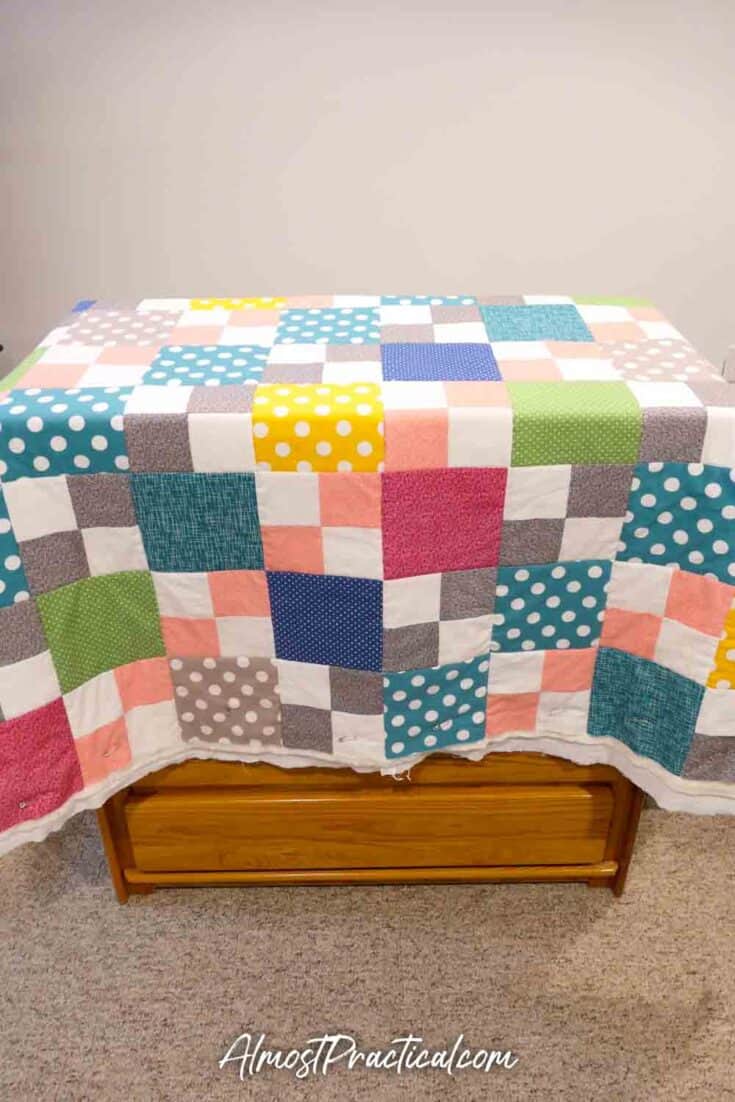 quilt draped over a chest of drawers