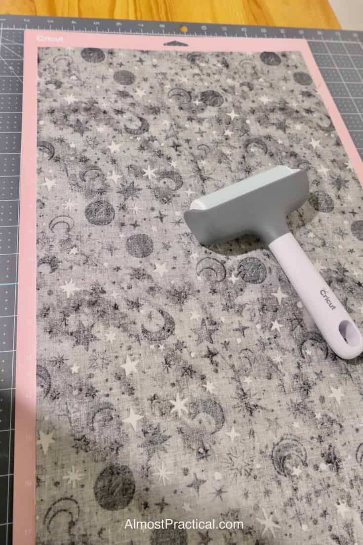 attaching fabric to pink Cricut mat with brayer