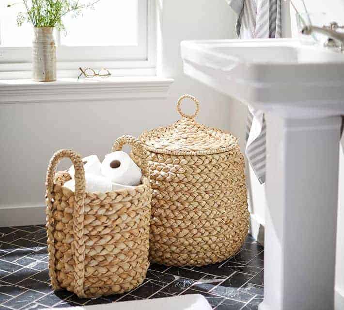 Pottery Barn baskets in bathroom holding toilet paper rolls.