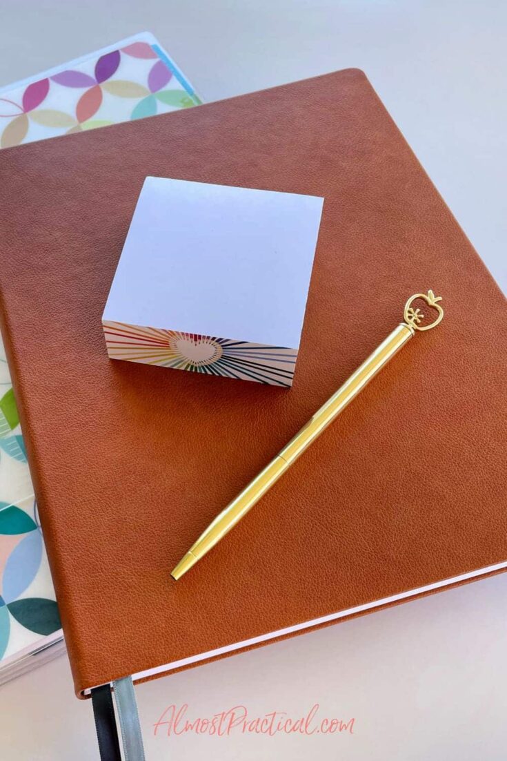 sticky note cube and gold ballpoint pen with an apple shape on top