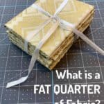 fat quarter stack of fabric in cream and gold tied with a white ribbon