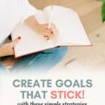 woman wearing jeans writing in notebook while sitting cross legged on a wood floor