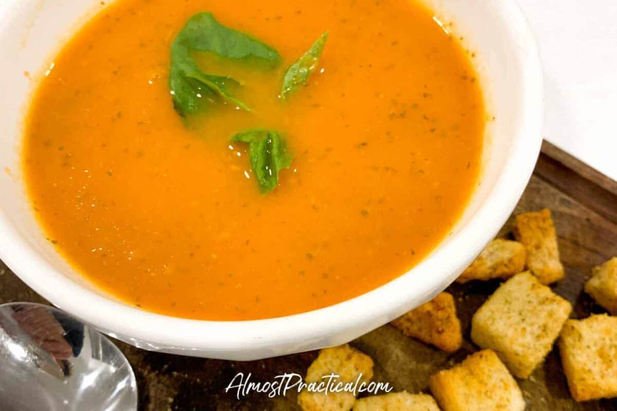 a bowl of homemade tomato basil soup with a side of croutons