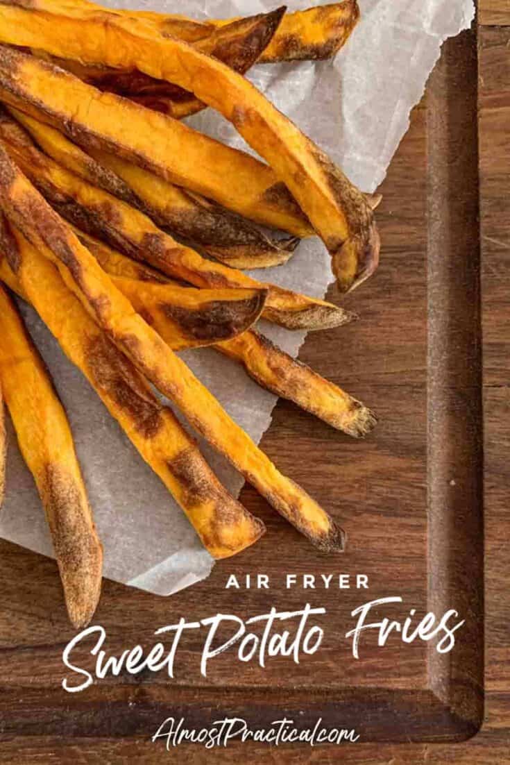 Sweet potato fries on parchment paper on a walnut cutting board.